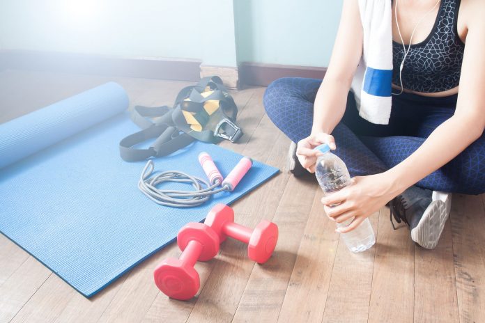 low-section-of-woman-with-water-bottle-by-dumbbells-royalty-free-image-769773831-1541537163